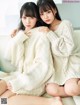 Two young women sitting on a couch wearing white sweaters.