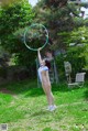 A woman in a white bathing suit holding a hula hoop.