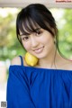 A woman in a blue dress holding a lemon.