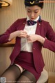 A woman in a red uniform is sitting on a chair.