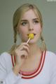 A woman holding a yellow lollipop in her mouth.