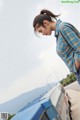 A woman leaning against a blue van on the side of a road.