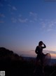 A woman standing on top of a hill next to the ocean.