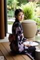 A woman sitting on a wooden table holding a cup of tea.