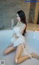 A woman in a white lingerie sitting in a bathtub.