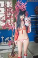 A woman in a red and white bikini holding a cat mask.